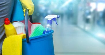 Cleaning lady with a bucket and cleaning products on blurred background .